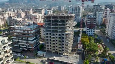 İşçiler binanın tepesine kirişler ve levhalar yerleştirirken İHA takım çalışmasını yakalıyor.