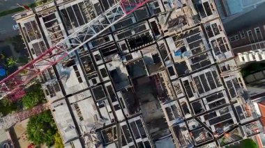 Drone, güneş ışığında ahşap kalıplar ve inşaat panelleri düzenleyen işçileri gösteriyor.