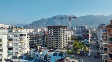 Beton iskelet boyunca büyük paneller düzenleyen işçilerin yakın görüntüsü.