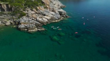 Güneşli gökyüzünün altında SUP tahtasında oturan çocuklu ebeveyn.