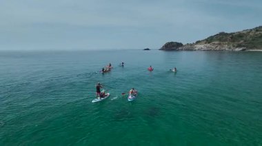 Turkuaz sularda kayalıkların yakınında dinlenen renkli tahtalar.