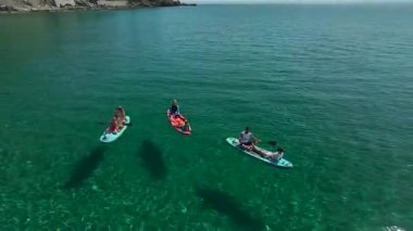 Atlılar dağların yakınındaki turkuaz denizde kürek çekiyorlar..