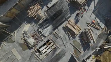 Açık çalışma alanı boyunca sıralanmış inşaat demirleri, keresteler ve tahtalar.