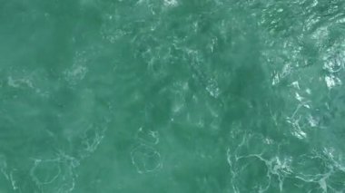 Turkuaz deniz tarafından şezlonglarla dolu ahşap rıhtım manzaralı İHA..