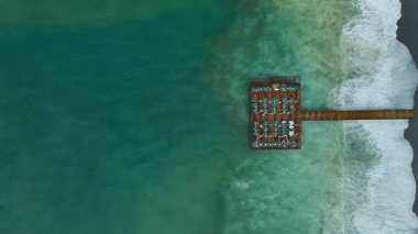 Drone, iskele silueti ve okyanusun dramatik zıtlığını vurguluyor.