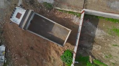 Toprak ve kayalarla çevrili damperli kamyonun drone görüntüsü.