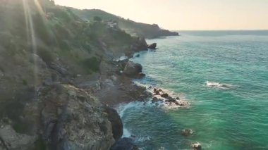 Akdeniz dalgalarının yanında büyük kayalar duruyor.