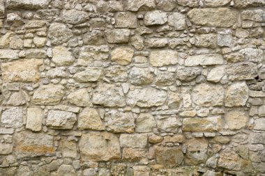 Texture of a stone wall with many big brown and grey stones armed with cement. Old castle stone wall texture background for medieval usage. Part of a stony building as a background