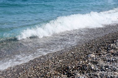 Arka planda deniz ve kumsal olan çakıl taşları bankası. Türkiye 'de Kemer, Antalya' da deniz kıyısında çakıl ve su