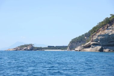 Türkiye 'de seyahat etmek Ege Denizi ve kayalık ada manzarası tabiat beldeleri güzel manzaralı tatil köyleri yaz mevsimi. Derin mavi deniz suyunun üzerinde büyük sallanan kıyılar. Serinlemek için lüks yerler