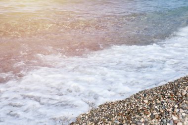 Arka planda deniz ve kumsal olan çakıl taşları bankası. Türkiye 'de Kemer, Antalya' da deniz kıyısında çakıl ve su