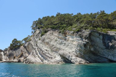 Türkiye 'de seyahat etmek Ege Denizi ve kayalık ada manzarası tabiat beldeleri güzel manzaralı tatil köyleri yaz mevsimi. Derin mavi deniz suyunun üzerinde büyük sallanan kıyılar. Serinlemek için lüks yerler