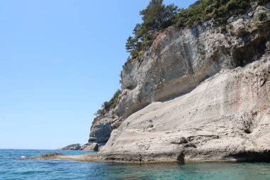 Türkiye 'de seyahat etmek Ege Denizi ve kayalık ada manzarası tabiat beldeleri güzel manzaralı tatil köyleri yaz mevsimi. Derin mavi deniz suyunun üzerinde büyük sallanan kıyılar. Serinlemek için lüks yerler