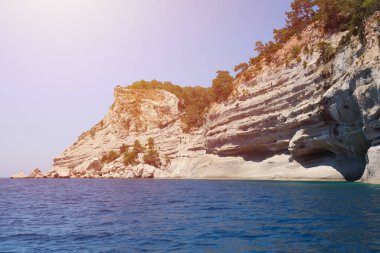 Türkiye 'de seyahat etmek Ege Denizi ve kayalık ada manzarası tabiat beldeleri güzel manzaralı tatil köyleri yaz mevsimi. Derin mavi deniz suyunun üzerinde büyük sallanan kıyılar. Serinlemek için lüks yerler