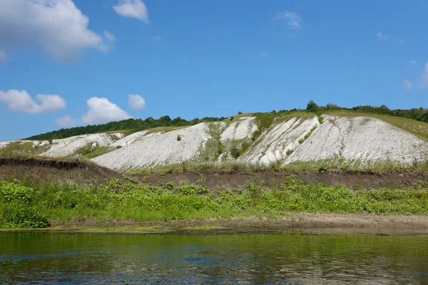 stock image Ancient multimillion chalk mountains on the steppe surface of earth. White chalk mountains in landscape with river and green trees