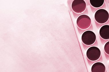 Yeni bir suluboya seti, mavi çizimler şeklinde soyut bir suluboya resmi gösteren bir kağıt yaprağının üzerinde bulunuyor. Görüntü tonu Viva Magenta, 2023 yılının rengi