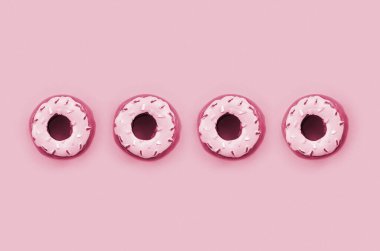 Birçok küçük plastik donut arka planda yatar. Düz çizgi çizilmiş. Üst Manzara. Görüntü tonu Viva Magenta, 2023 yılının rengi