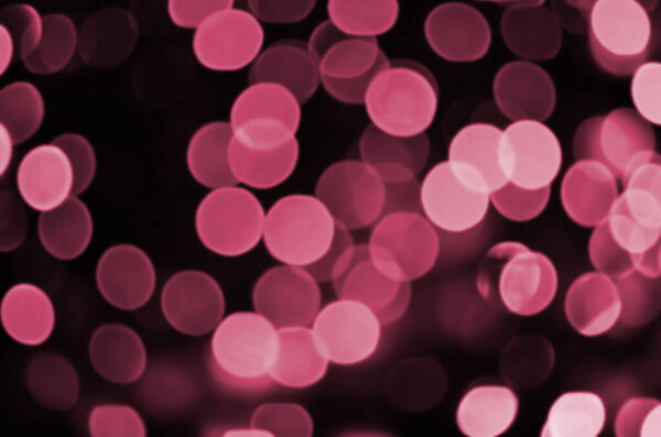 Abstract background image with bokeh effect. Many brightly ed circular shapes on a dark background. Image toned in Viva Magenta, color of the 2023 year