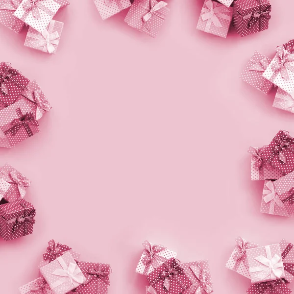 Piles of a small colored gift boxes with ribbons lies on a violet background. Minimalism flat lay top view pattern. Image toned in Viva Magenta, color of the 2023 year