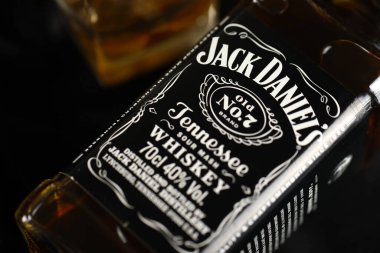 KYIV, UKRAINE - 4 Mayıs 2022 Jack Daniels orjinal alkol şişesi ahşap masa üzerinde arka planda siyah kumaş. Elit alkol üretimi