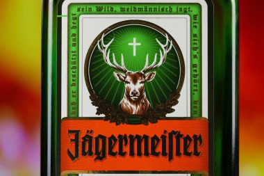 KYIV, UKRAINE - 4 Mayıs 2022 Jagermeister orijinal alkol şişesi ahşap masada, arka planda kırmızı şömine var. Elit alkol üretimi