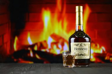 KYIV, UKRAINE - 4 Mayıs 2022 Hennessy Çok Özel alkol şişesi ahşap masada arka planda kırmızı şömine. Elit alkol üretimi