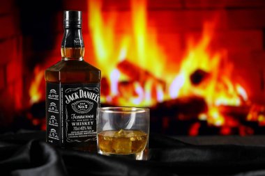 KYIV, UKRAINE - 4 Mayıs 2022 Jack Daniels orijinal alkol şişesi ahşap masada, arka planda kırmızı şömine var. Elit alkol üretimi