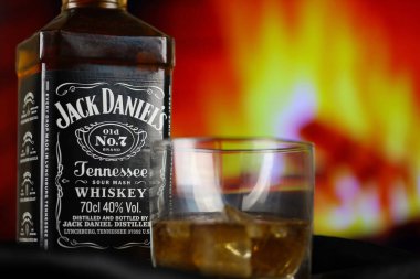 KYIV, UKRAINE - 4 Mayıs 2022 Jack Daniels orijinal alkol şişesi ahşap masada, arka planda kırmızı şömine var. Elit alkol üretimi
