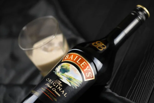 Kyiv Ukraine May 2022 Baileys的原装酒精瓶放在木制桌子上 背景为黑色面料 精英酒精生产 — 图库照片