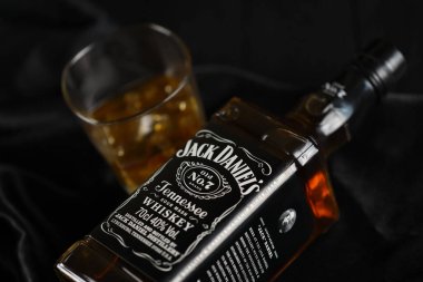 KYIV, UKRAINE - 4 Mayıs 2022 Jack Daniels orjinal alkol şişesi ahşap masa üzerinde arka planda siyah kumaş. Elit alkol üretimi