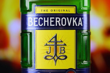 KYIV, UKRAINE - 4 Mayıs 2022 Becherovka orijinal alkol şişesi ahşap masada, arka planda kırmızı şömine var. Elit alkol üretimi