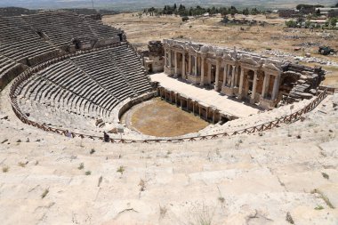ANTALYA, TURKEY - 15 Mayıs 2021 Pamukkale yakınlarındaki antik Hierapolis kentinde güneşli bir günde amfitiyatro harabeleri. Büyük blokları ve sütunları olan eski tarihi binaların parçaları.