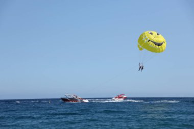 ANTALYA, TURKEY - 15 Mayıs 2021 Deniz plajı yakınlarındaki mavi bir gökyüzünde Parasailing. Parasailing Türkiye 'de turistler arasında popüler bir eğlence aktivitesidir.