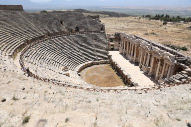 ANTALYA, TURKEY - 15 Mayıs 2021 Pamukkale yakınlarındaki antik Hierapolis kentinde güneşli bir günde amfitiyatro harabeleri. Büyük blokları ve sütunları olan eski tarihi binaların parçaları.