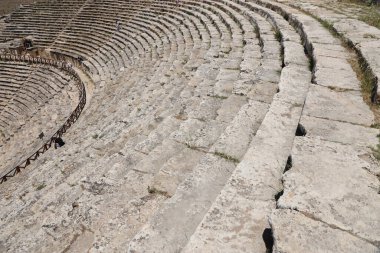 ANTALYA, TURKEY - 15 Mayıs 2021 Pamukkale yakınlarındaki antik Hierapolis kentinde güneşli bir günde amfitiyatro harabeleri. Büyük blokları ve sütunları olan eski tarihi binaların parçaları.