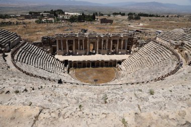 ANTALYA, TURKEY - 15 Mayıs 2021 Pamukkale yakınlarındaki antik Hierapolis kentinde güneşli bir günde amfitiyatro harabeleri. Büyük blokları ve sütunları olan eski tarihi binaların parçaları.