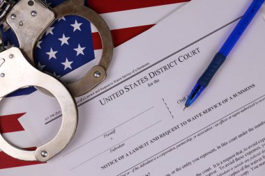 Bölge mahkemesi dava bildirisi ve mahkeme celbinden feragat talebinde bulundu. Elleri kelepçeli kağıtlar ve mavi kalemle ABD bayrağını kapatın.