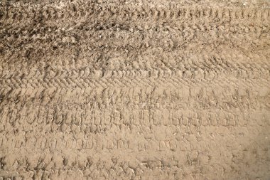 Çamurda tekerlek izi. Islak bir çayırdaki kahverengi çamurda traktör ya da ağır off-road arabası izleri.