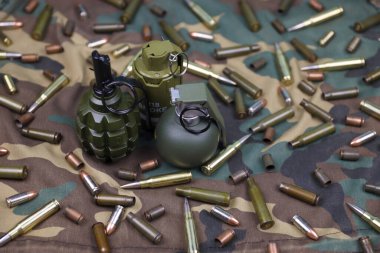 Kamuflaj arka planında farklı cephane ve el bombaları var. Savaşa hazırlanıyorum. Silah bulundurma.