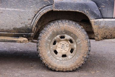 Çamur yolu olan bir kırsal alanda tekerlek yakın çekim. Off-road 4x4 SUV otomobil çamurlu yol alanında sürdükten sonra ditry body ile