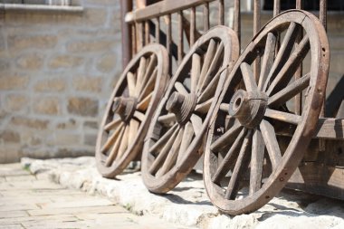 At arabaları için üç eski ahşap tekerlek Tahta duvara yaslanmış perspektifte