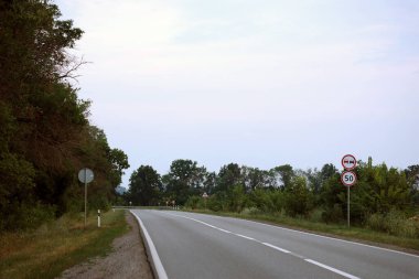 Akşam vakti boş asfalt yolu ve farklı çim ve çiçeklerden oluşan çiçek tarlası. Kenar mahalle manzarası