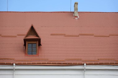 Eski kiremit şeklinde dekoratif metal çatı kiremitleri. Metal bir profilden evin çatısına yakın.