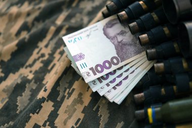Ukrayna ordu makineli tüfek mermileri, kelepçeler ve askeri üniformanın üzerinde bir sürü Hryvnia banknotları. Ukrayna 'daki savaş sırasında rüşvet ve savaş suçları kavramı