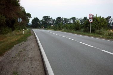 Akşam vakti boş asfalt yolu ve farklı çim ve çiçeklerden oluşan çiçek tarlası. Kenar mahalle manzarası