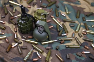 Kamuflaj arka planında farklı cephane ve el bombaları var. Savaşa hazırlanıyorum. Silah bulundurma.