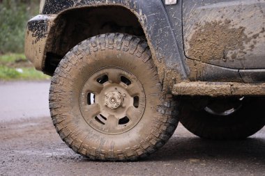 Çamur yolu olan bir kırsal alanda tekerlek yakın çekim. Off-road 4x4 SUV otomobil çamurlu yol alanında sürdükten sonra ditry body ile