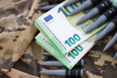 Avro banknotları ve Ukraynalı bir askerin kamuflaj üniformasında bir makineli tüfek kemeri. Savaş finansmanı, rüşvet ya da bağış kavramı. Ukrayna 'ya ABD' den yardım
