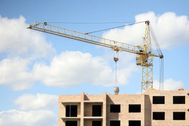 İnşaat halindeki binaları ve çok katlı evleri olan büyük bir şantiye manzarası. Mavi gökyüzü arka planında kule vinçleri devrede. Konut yenileme konsepti. İşlem sırasında turna