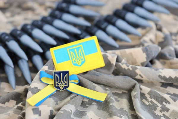 Ukrainian symbol and a machine gun belt on the camouflage uniform of a Ukrainian soldier. The Concept of war in Ukraine, patriotism and protecting your country from russian occupiers
